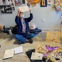 a woman holding up a piece of paper in a messy room