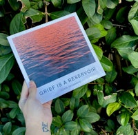 a person holding up a book with the title grief is retribution