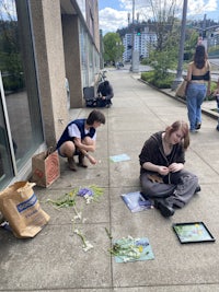 a group of people sitting on the sidewalk