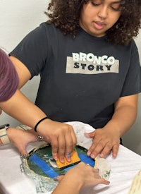 two girls working on a piece of paper with bronco story written on it